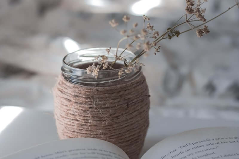 Glass jar repurposed into a decorative vase with dried stems