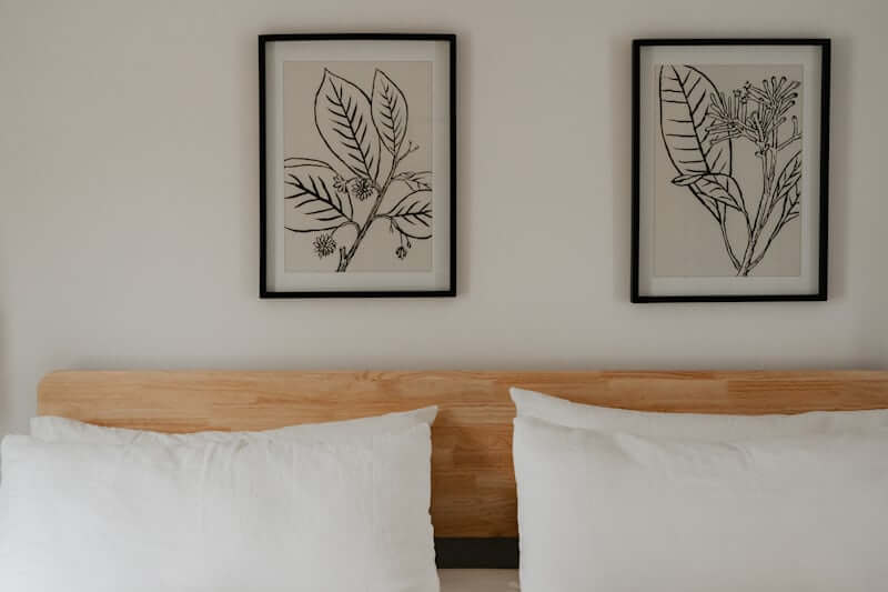 Soft botanical wall art above a bed in a cozy bedroom
