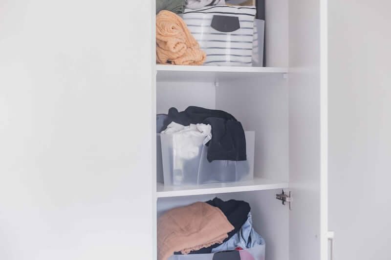 Clear labeled bins organizing a small apartment closet