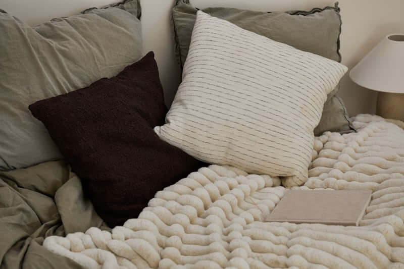 Chunky knit throw blanket folded at the foot of a bed